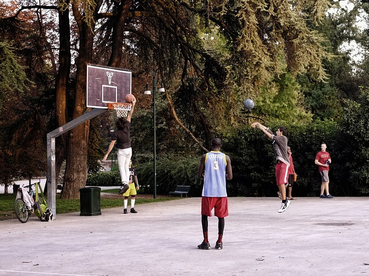 Jugendliche im Park, die Basketball spielen.